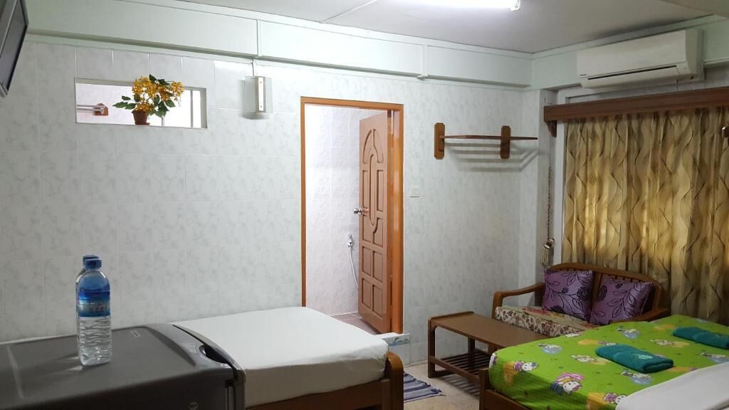 A room with a bed, a small table, a chair, a water bottle, and a door.