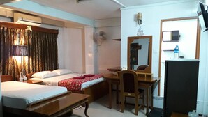 A hotel room with two beds, a desk, a chair, a mirror, a television, and a panda plush toy on the floor. - Chan Myae Guest House (Yangon)