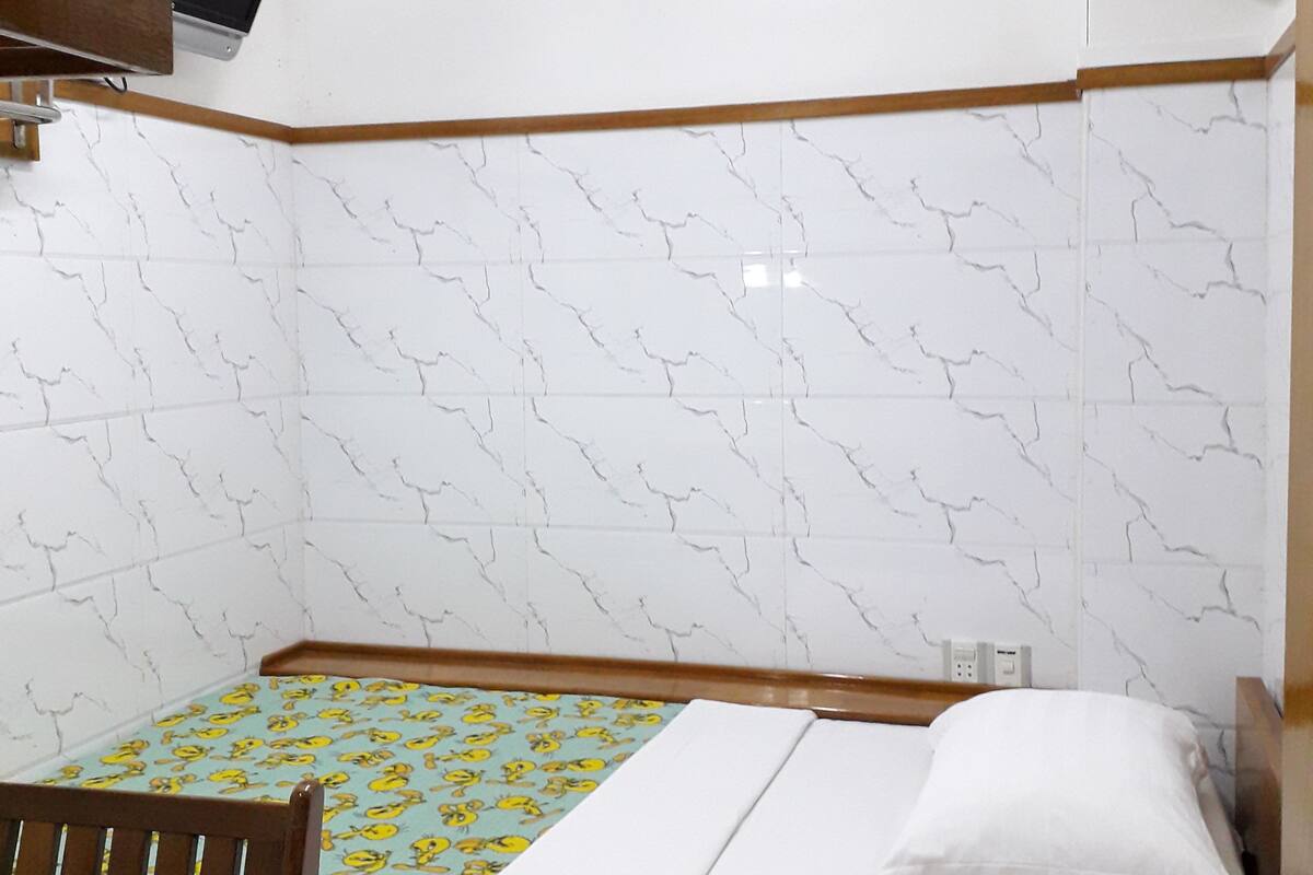 A small, neatly arranged room with a bed, a desk, and a chair.