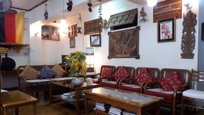 A traditional room with wooden furniture, a small table with a vase of flowers, and various wall decorations including framed pictures and a sign. - Chan Myae Guest House (Yangon)