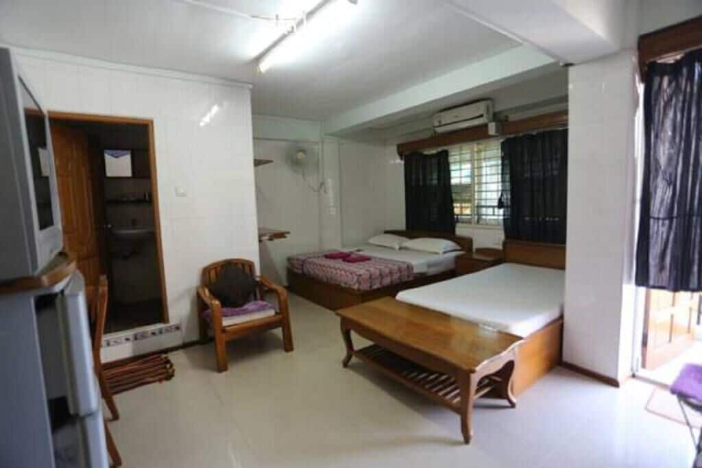 A compact room with a bed, a chair, a small table, and a television.