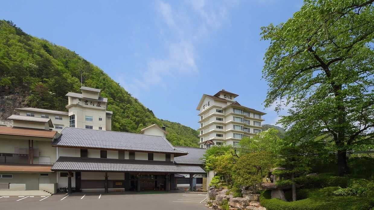 A hotel with multiple buildings, a parking lot, and lush greenery.