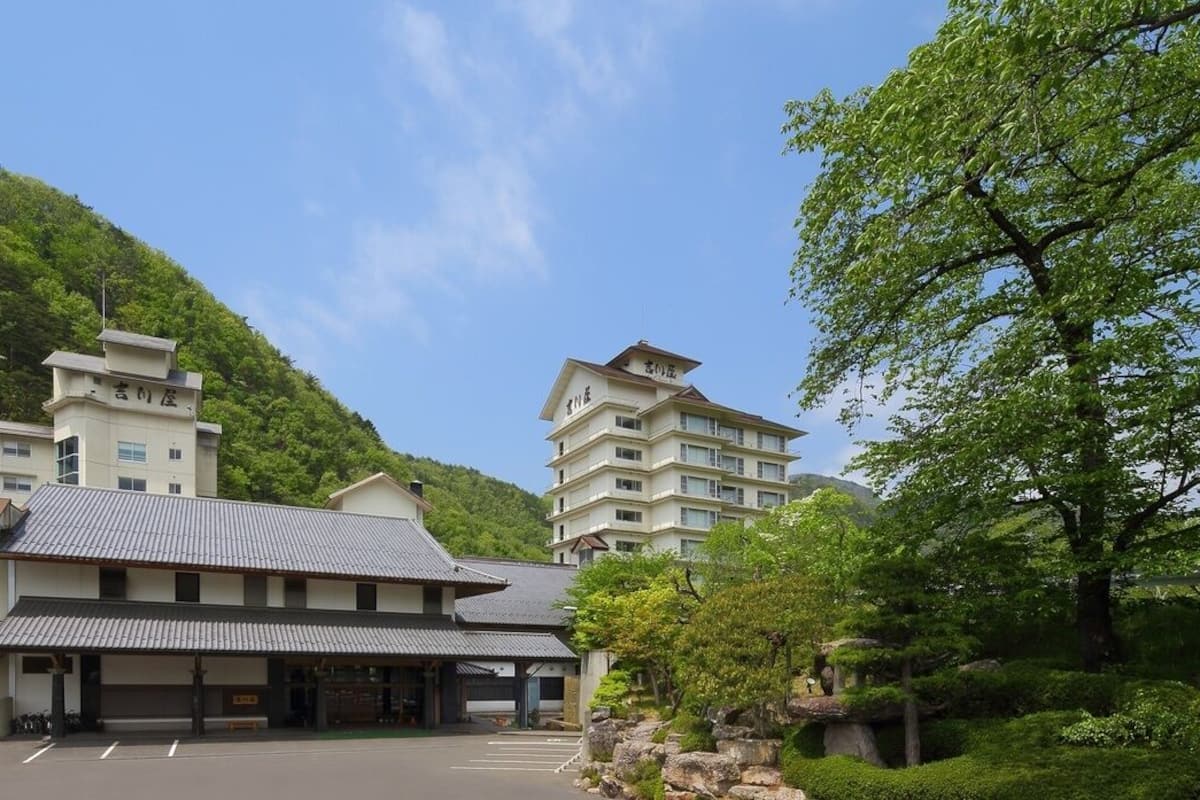 A hotel with multiple buildings, a parking lot, and lush greenery.