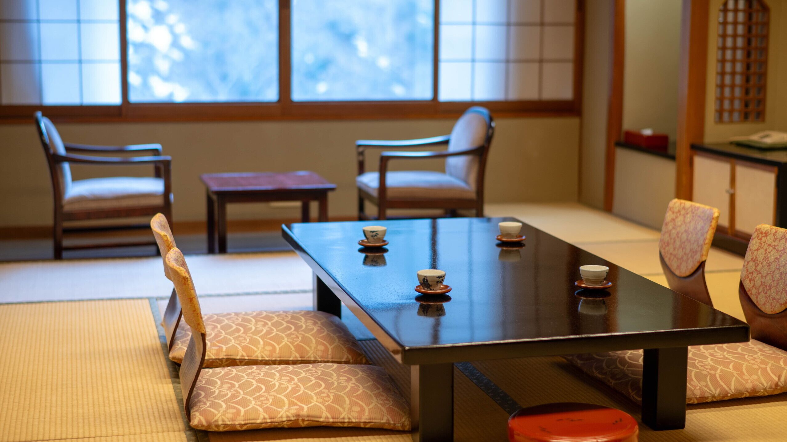 A traditional Japanese-style room with tatami flooring, a low table with cushions, and sliding doors.