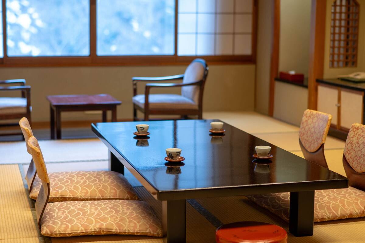 A traditional Japanese-style room with tatami flooring, a low table with cushions, and sliding doors.