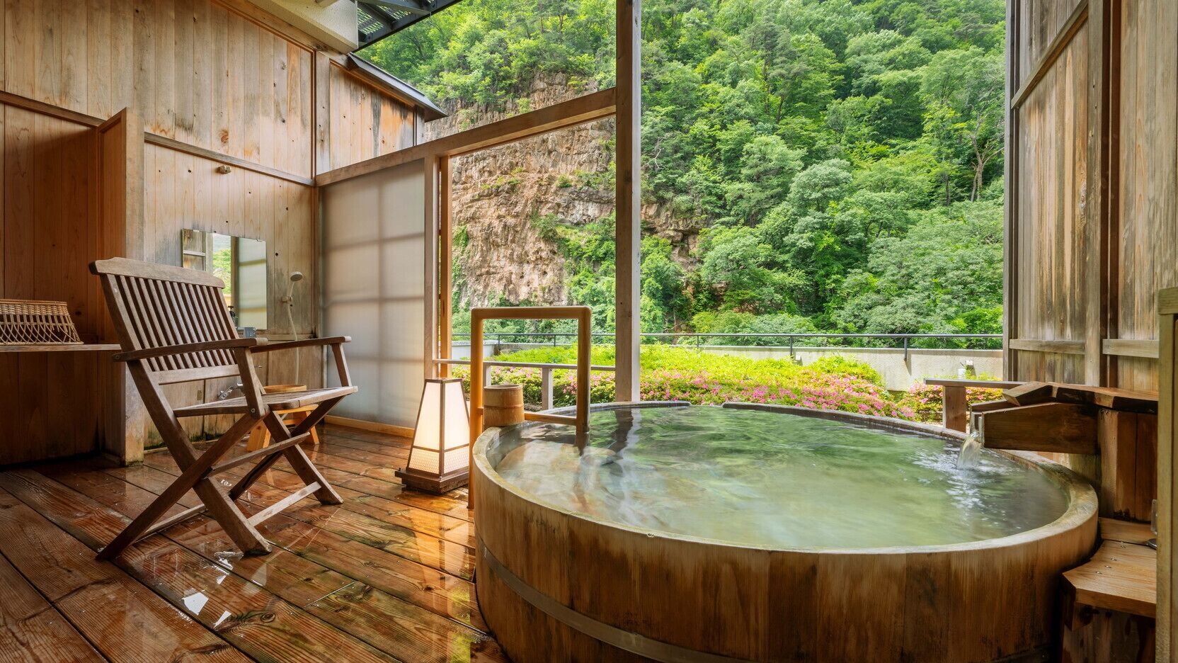 A wooden spa with a hot tub, wooden deck, and a view of lush greenery.