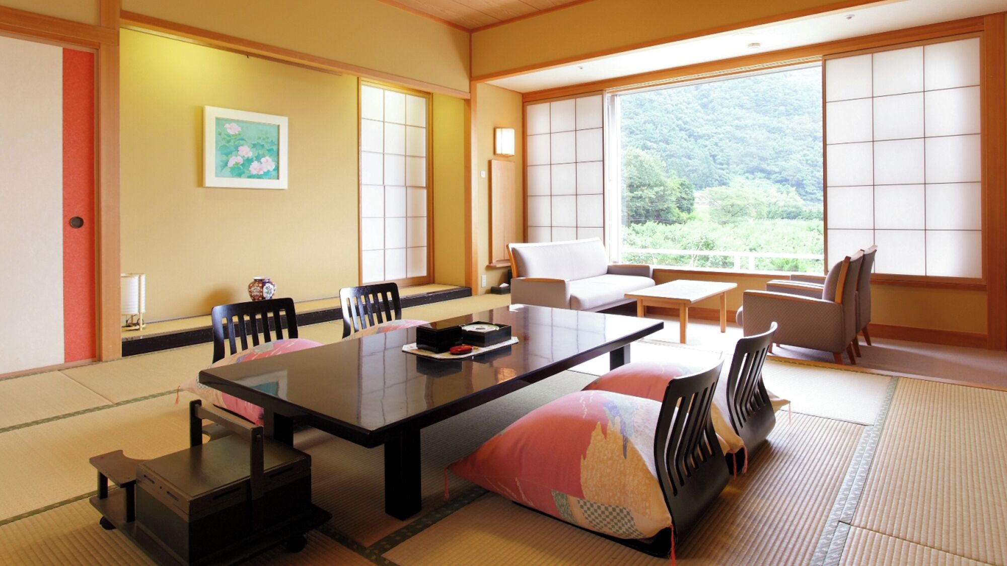 Ein traditioneller japanischer Raum mit Tatami-Bodenbelag, einem niedrigen Tisch, einer Couch und verschiebbaren Türen.