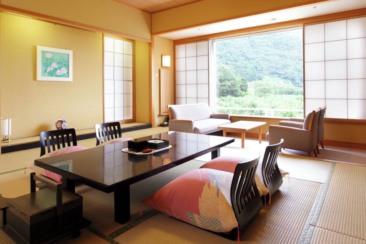 A traditional Japanese room with tatami flooring, a low table, a sofa, and sliding doors.