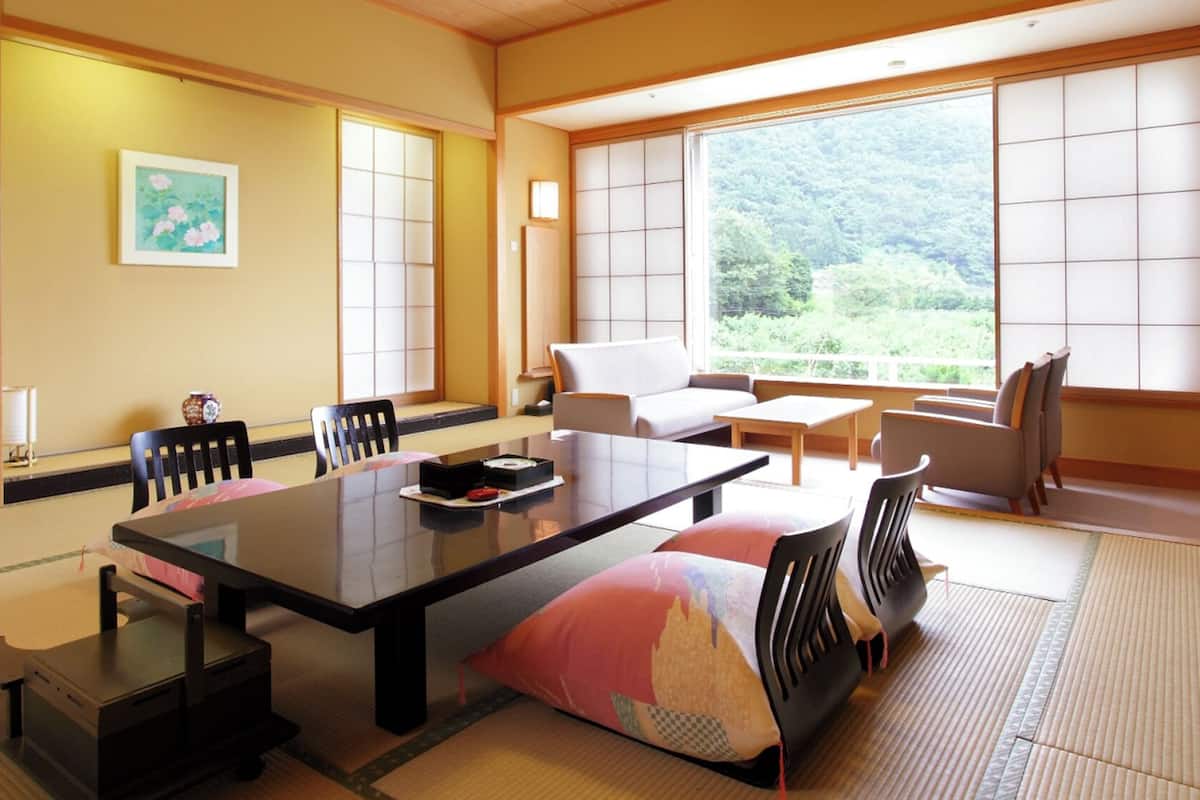 Ein traditioneller japanischer Raum mit Tatami-Bodenbelag, einem niedrigen Tisch, einer Couch und verschiebbaren Türen.