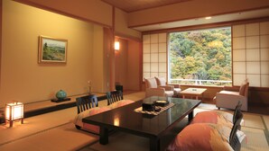 Ein traditioneller japanischer Raum mit Tatami-Boden, einem niedrigen Tisch und Sitzkissen.