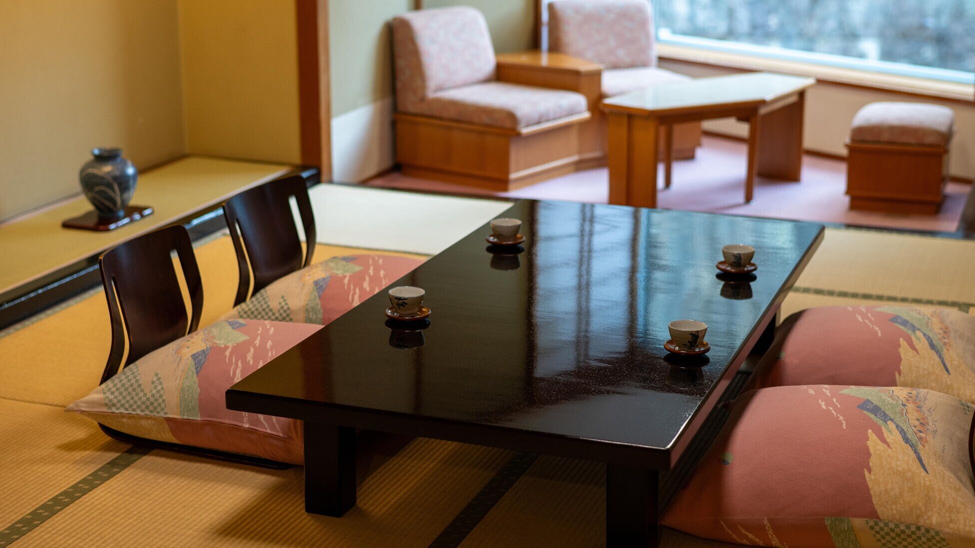 A traditional Japanese tatami mat room with a low table, cushions, and a tea set.