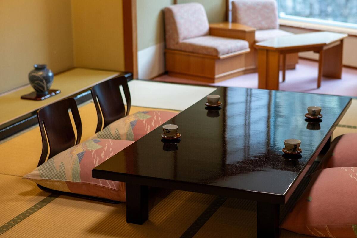 A traditional Japanese tatami mat room with a low table, cushions, and a tea set.