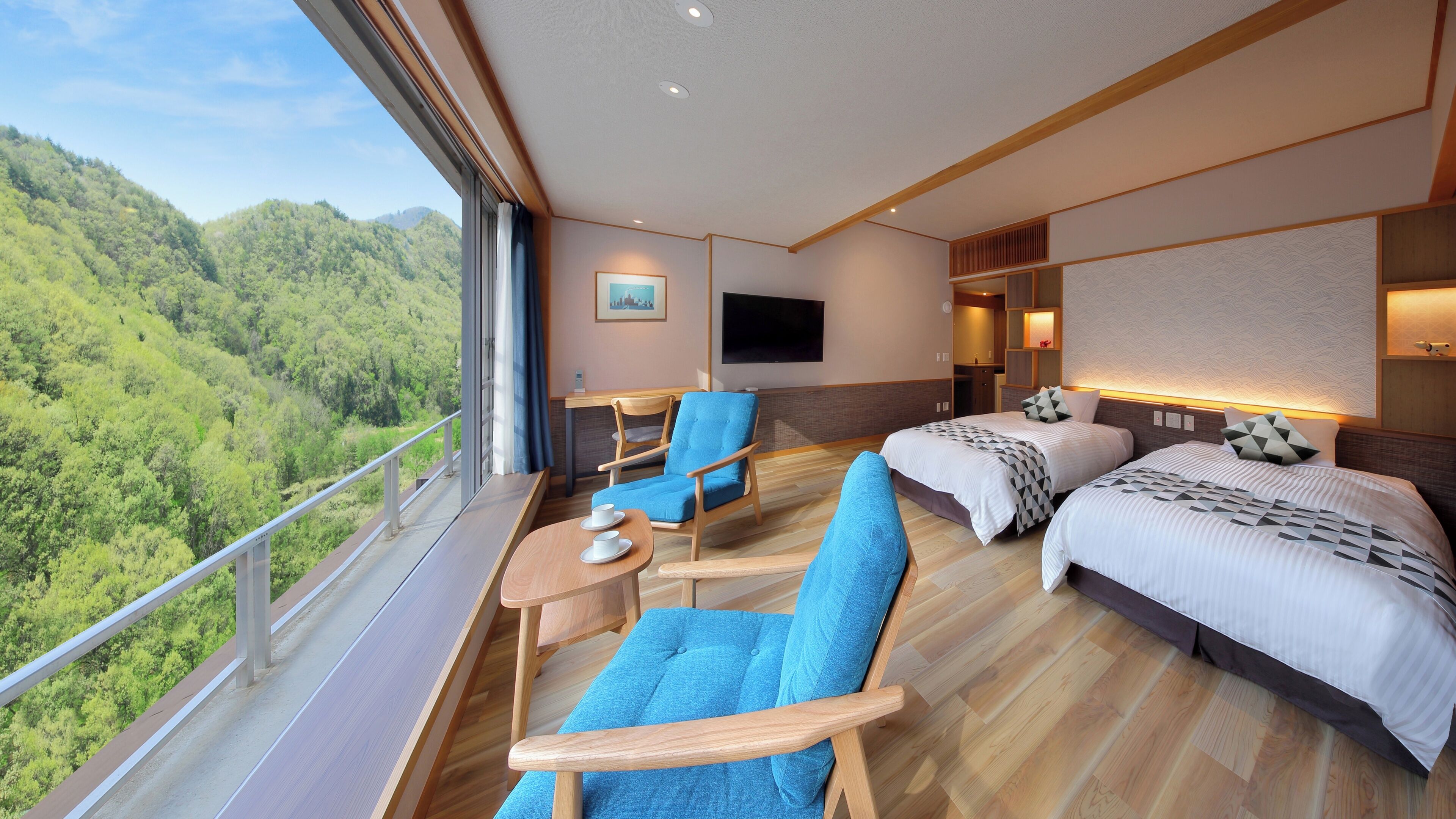 A hotel room with a balcony, two beds, a sofa, a chair, a TV, and a painting.
