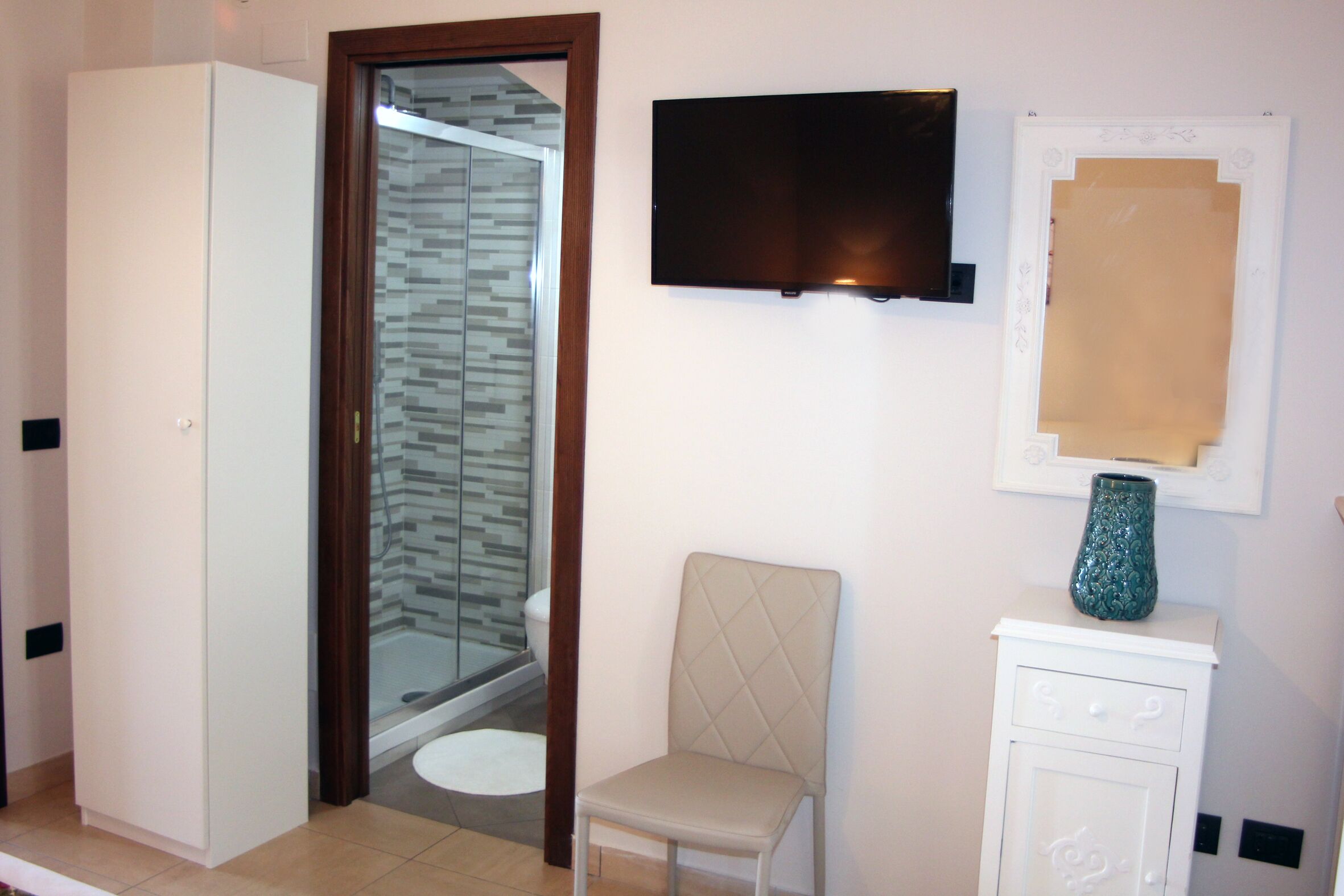 Un baño con ducha, inodoro y tocador con televisor y elementos decorativos.