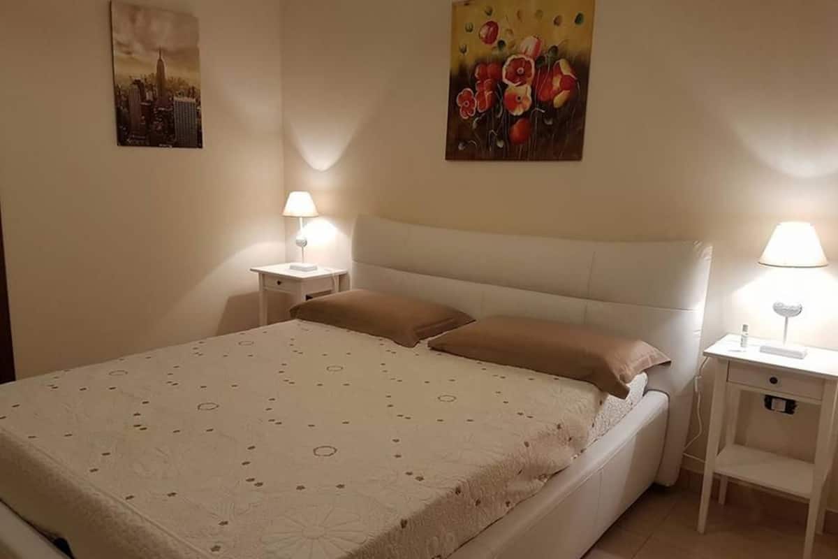 Une chambre à coucher avec un lit, deux tables de chevet et deux lampes.