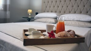 A neatly made bed with a tray of breakfast items including croissants, juice, and coffee cups. - B&B Atrium (Pompei)