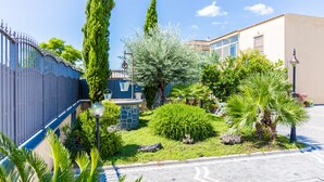 A courtyard with a fountain, various plants, and a building with a tiled roof. - B&B Atrium (Pompei)