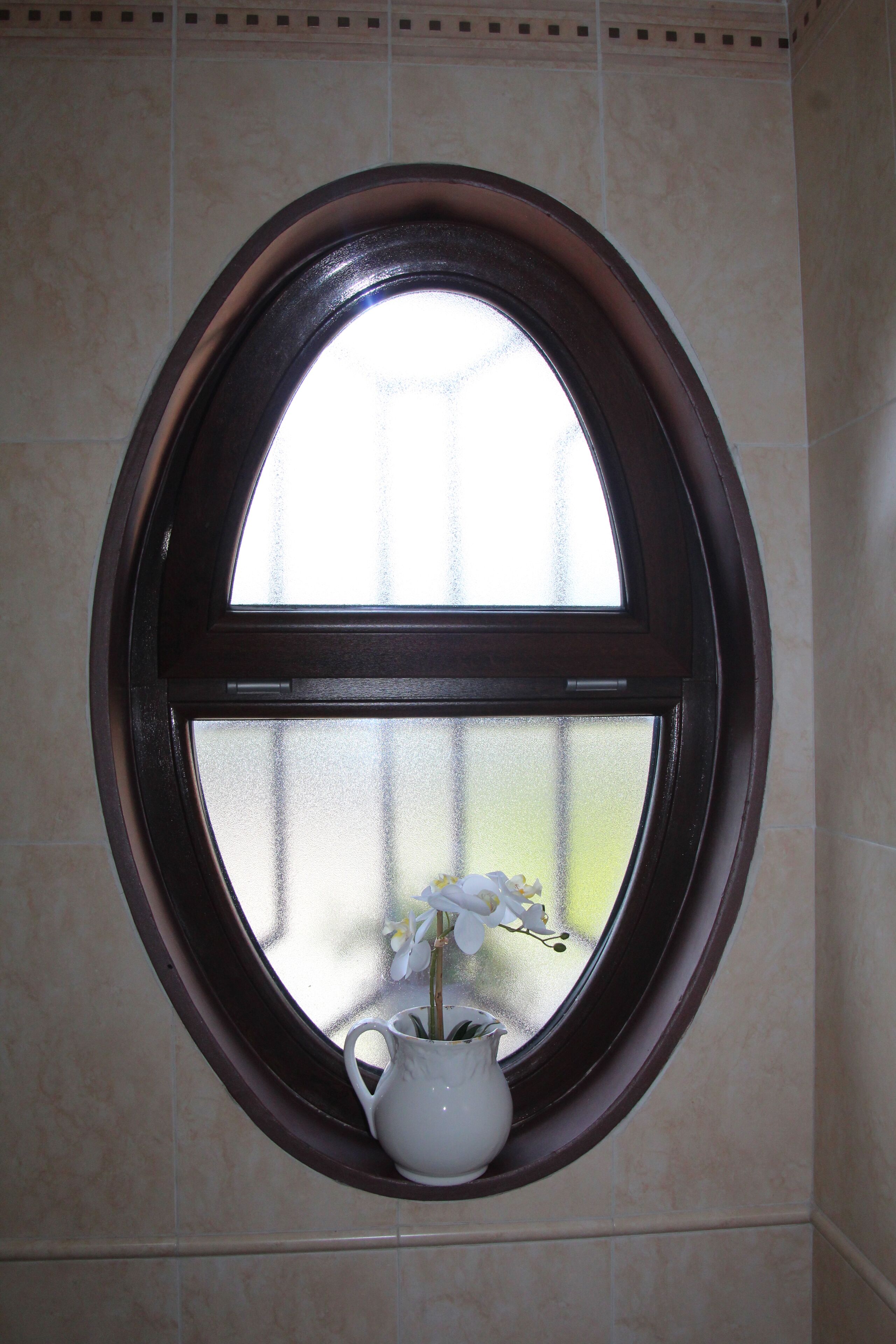 A window with a white vase containing flowers.