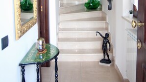 A staircase with a handrail, a green vase on the landing, and a small statue at the bottom. - B&B Atrium (Pompei)