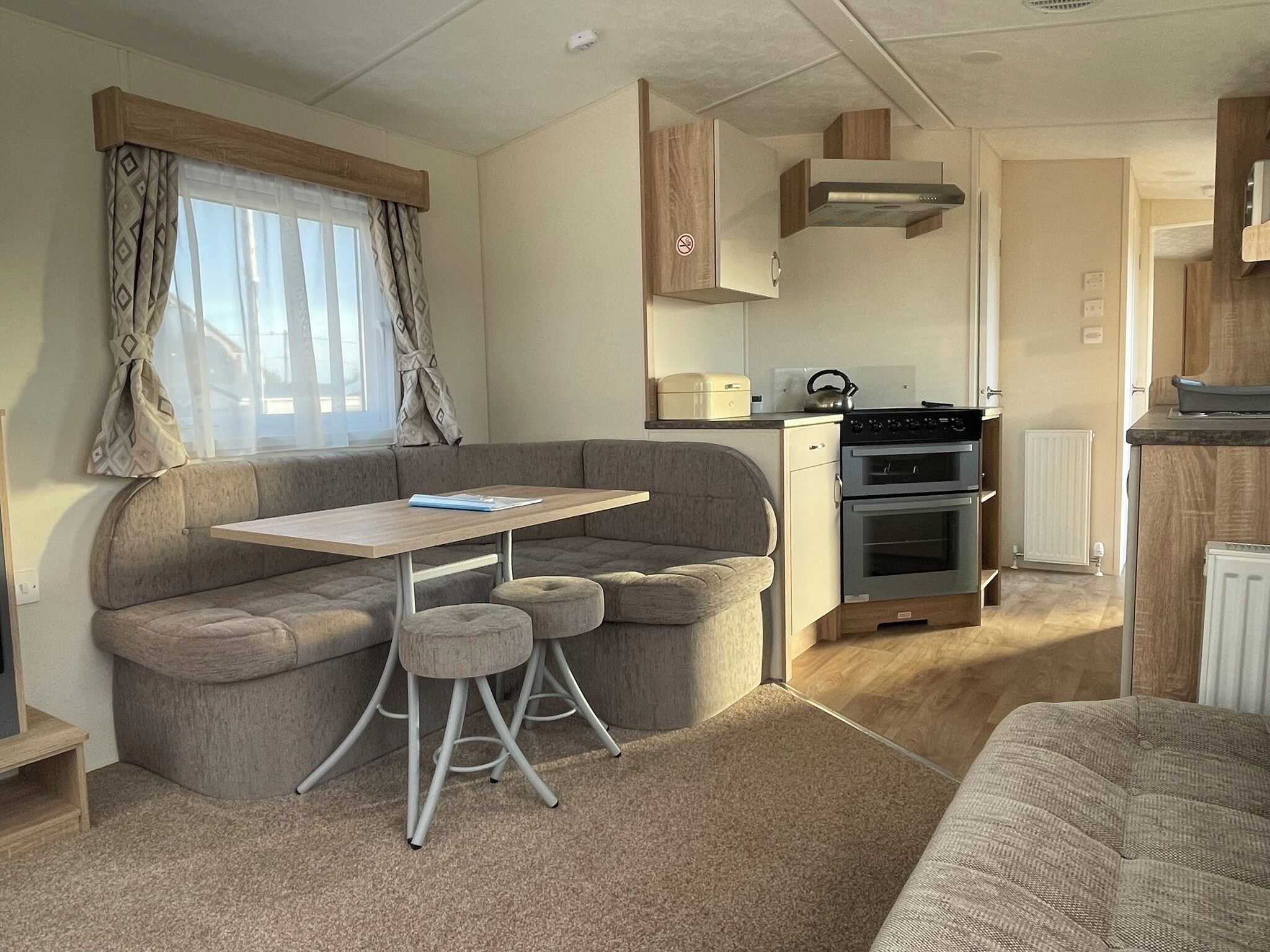 A compact RV interior with a kitchenette, a dining area, and a seating space.