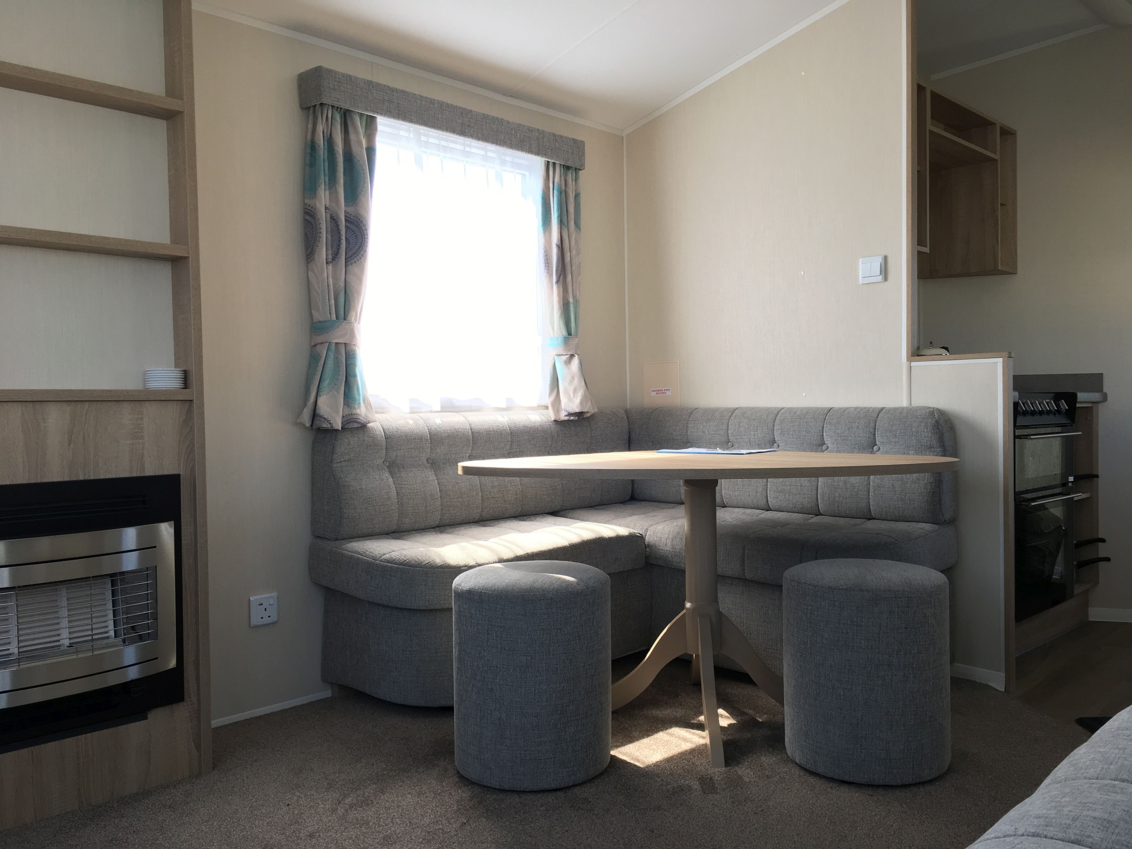 A compact living space with a built-in sofa, a small table, and a kitchenette area.