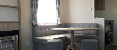 A compact living space with a built-in sofa, a small table, and a kitchenette area.