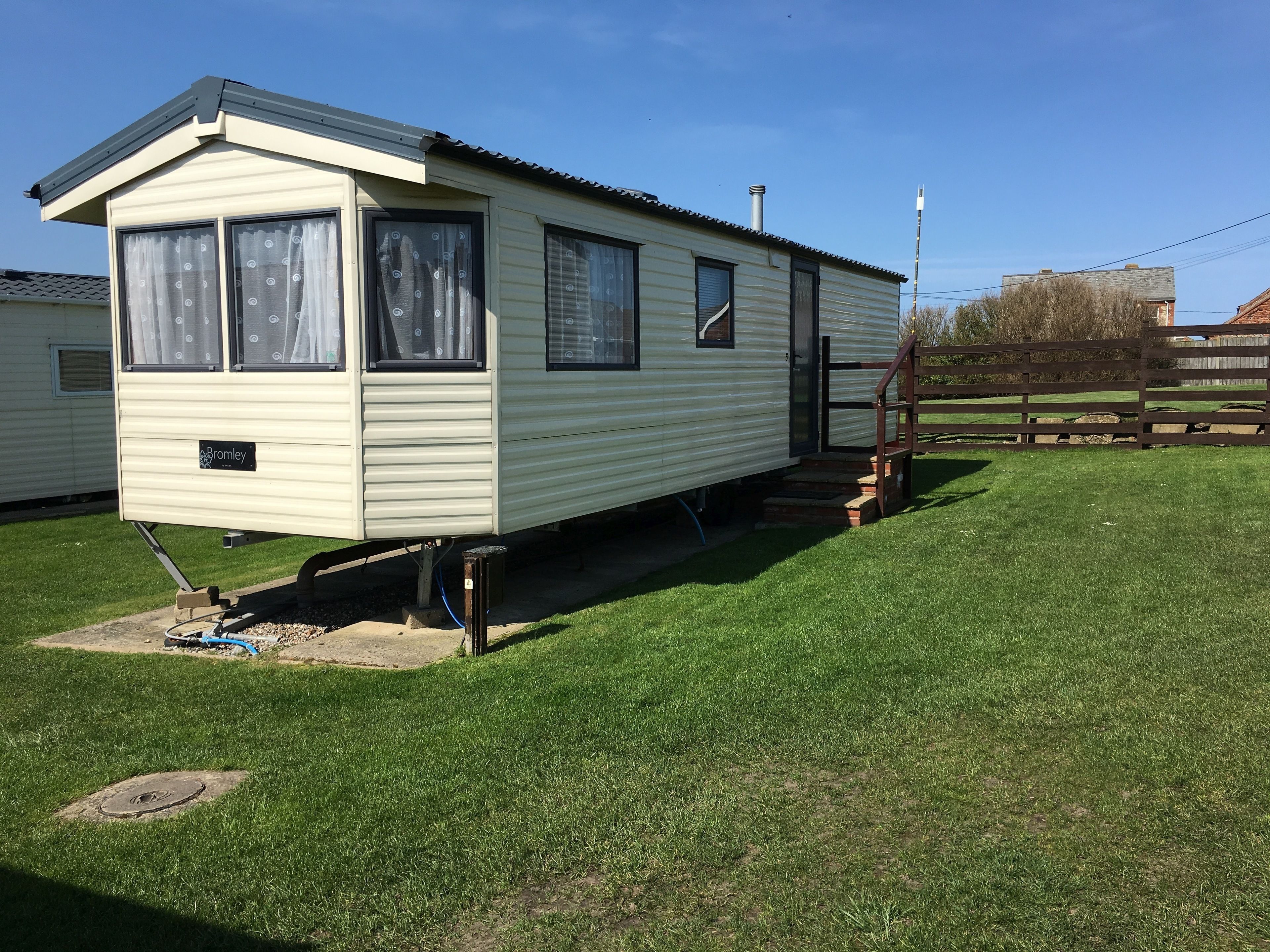 A mobile home with a front porch and a small staircase leading to the entrance.