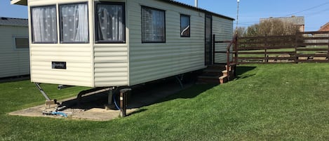 A mobile home with a front porch and a small staircase leading to the entrance.