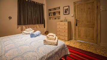Quarto com cama, penteadeira, porta e janela com cortinas.