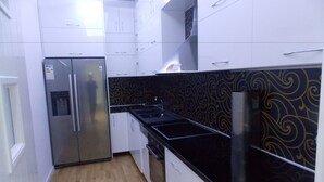 A kitchen with white cabinets, a black countertop, and a patterned backsplash. - Doka Apartments (Sarandë)