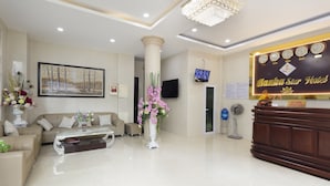 A hotel reception area with a reception desk, a television, a wall-mounted clock, and a framed painting. - Hanka Star Hotel (Nha Trang)