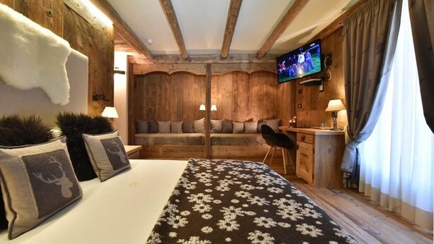 Una habitación acogedora con una cama, un escritorio y un televisor.