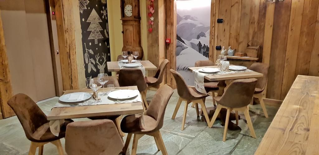 Zona pranzo con tavoli e sedie in legno, decorata con un murale raffigurante un paesaggio montano.