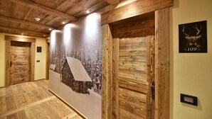 Un pasillo con paredes y techo de madera, un cartel grande con un paisaje nevado y una puerta con la inscripción '109'.