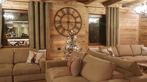 Una sala de estar acogedora con un gran reloj de pared de madera, un árbol de Navidad y dos sofás.