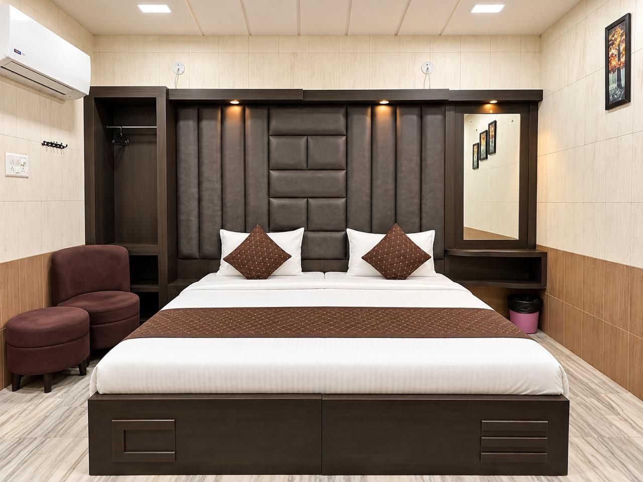 A modern hotel room with a large bed, a dark headboard, and a small seating area.