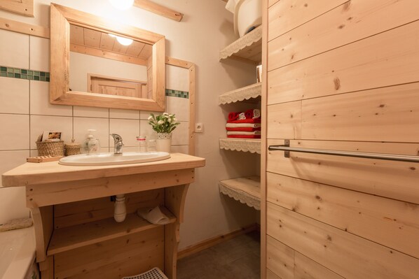 A wooden bathroom with a sink, mirror, and shelves.