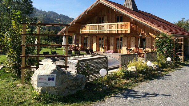Un chalet en bois doté d’un balcon, entouré de verdure et surplombant un ciel dégagé.