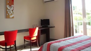 Habitación de hotel con cama, escritorio con silla, televisor y un cuadro en la pared.