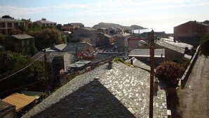 Una estrecha calle empedrada en un pueblo histórico, con edificios de piedra y cielo despejado.