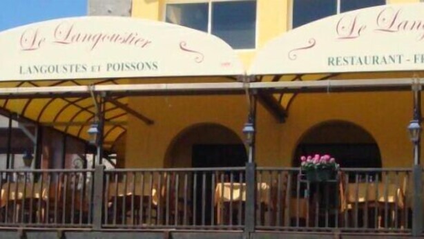 Un restaurante con un cartel que dice "Le Langoustier" y "RESTAURANTE - FRUTOS DEL MAR".