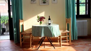 A room with a checkered tablecloth, two wicker chairs, a vase with flowers, a bottle of wine, and framed botanical prints on the wall. - Tenuta Guazzaura (Serralunga di Crea)