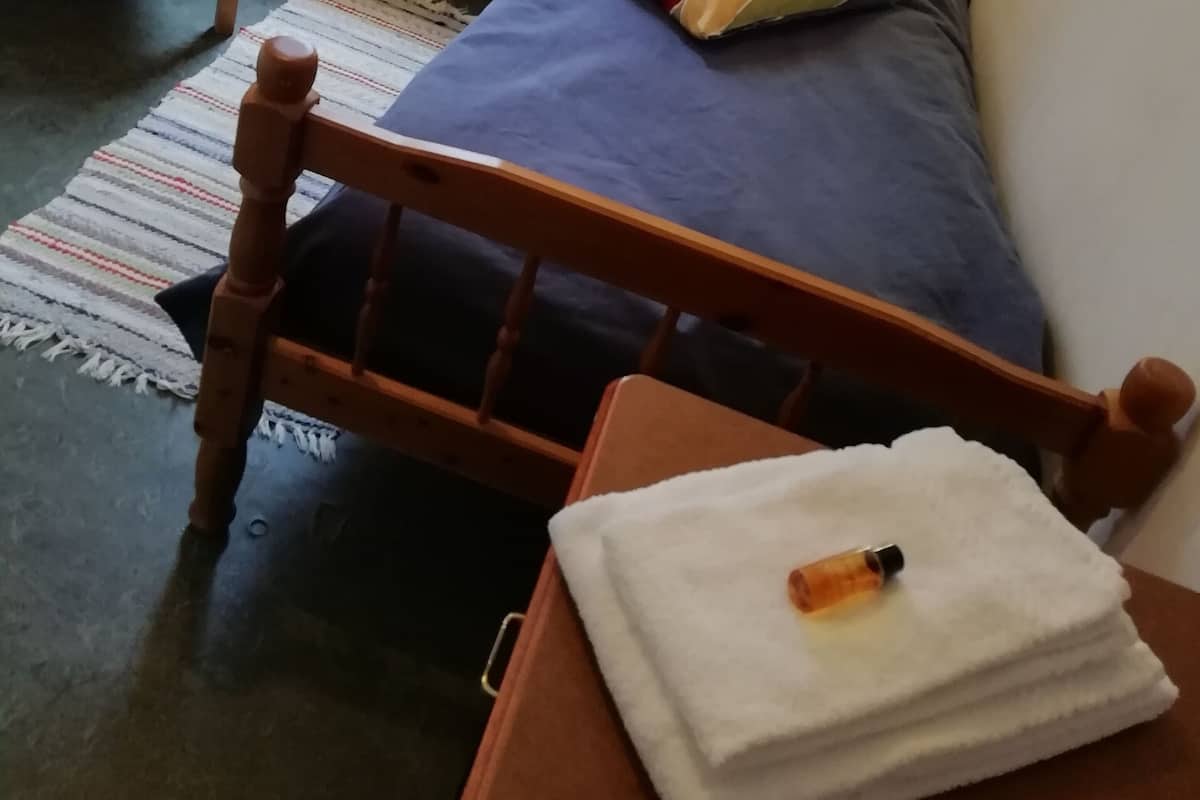 Une chambre à coucher avec un lit en bois, une chaise, une petite table et un radiateur.