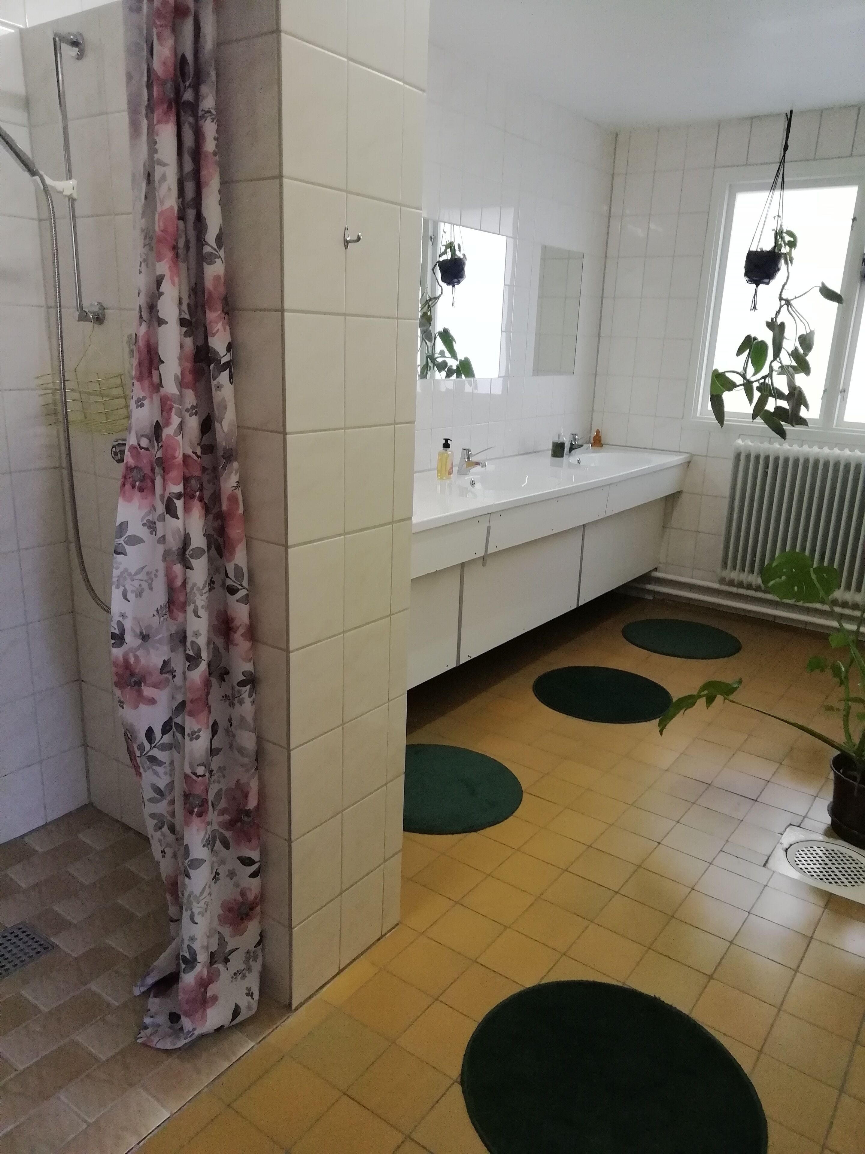 Une salle de bain équipée d’une douche, d’un lavabo, d’un miroir et d’un radiateur.