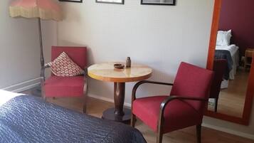 Una camera d'albergo con un letto, una sedia, un tavolino e uno specchio.