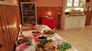 A buffet table with various dishes, a red tablecloth, and a clock on the wall.