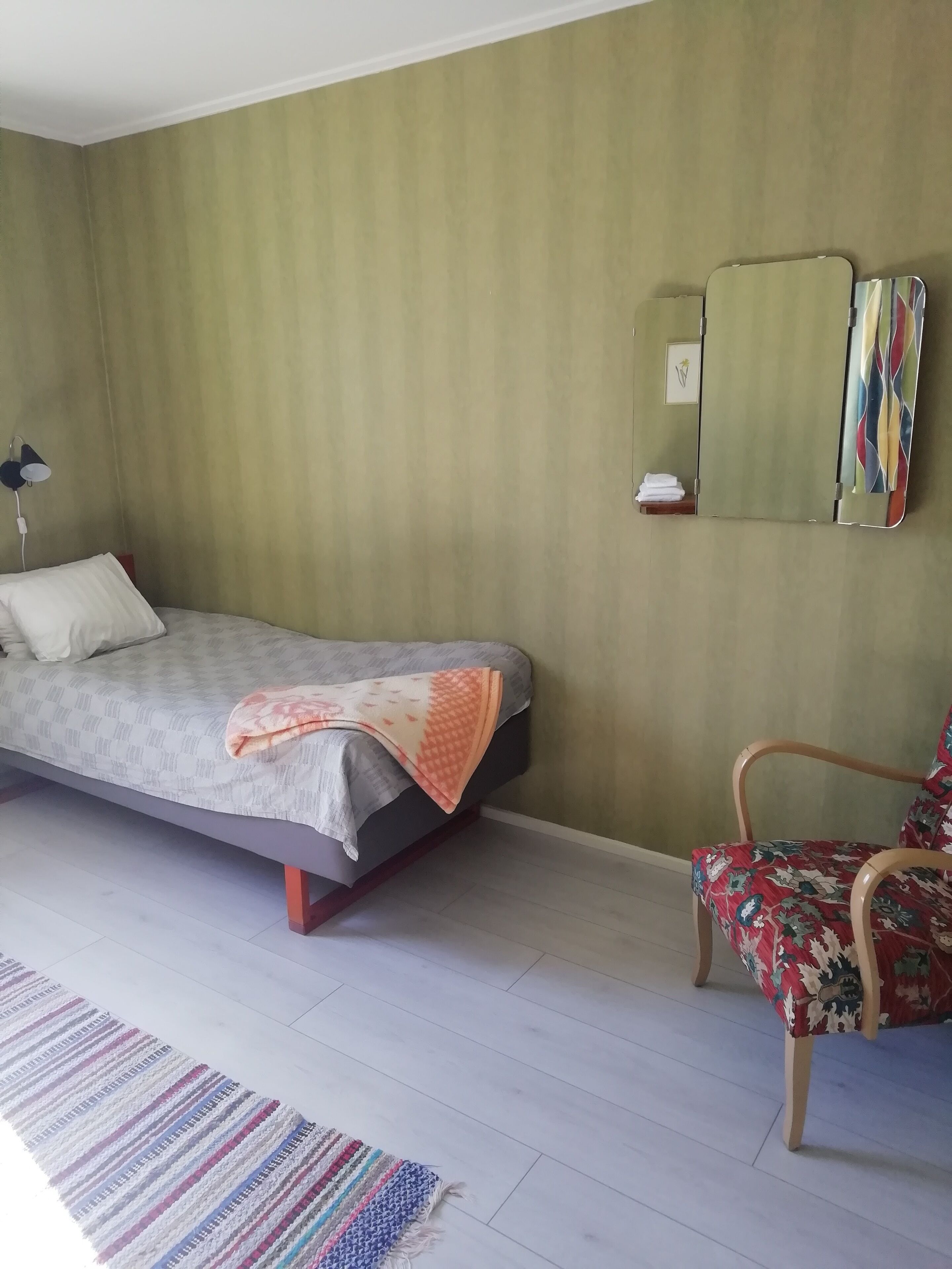 Une chambre à coucher comprenant un lit, une chaise, un miroir et une étagère fixée au mur.