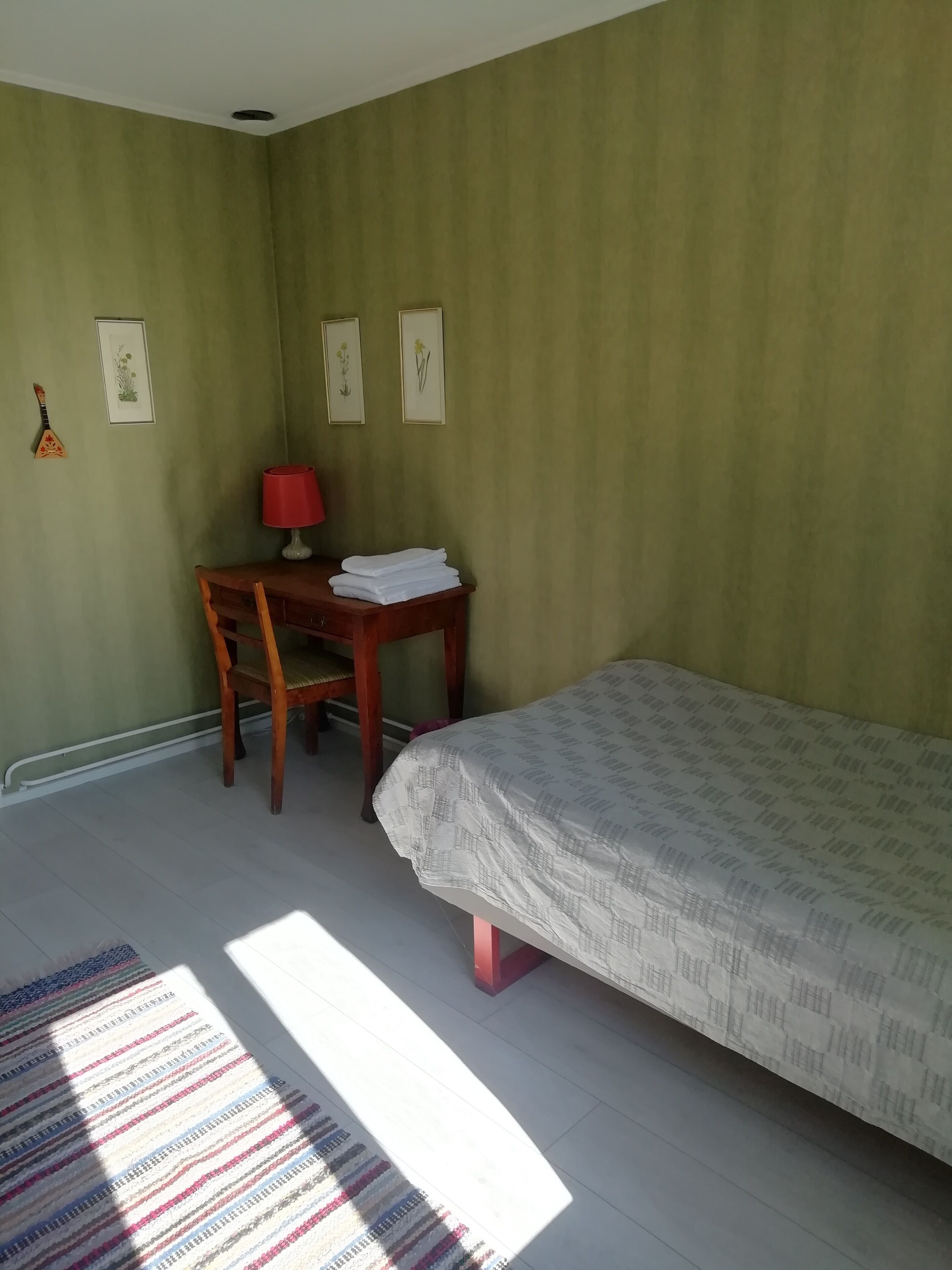 Un dormitorio con una cama, un escritorio, una silla y una lámpara.