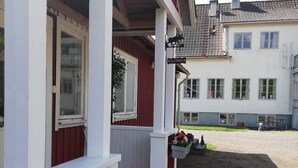 A building with a red and white facade, a covered porch with flower planters, and a clear sky.