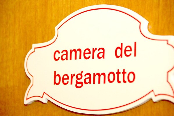 Un letrero con el texto 'camera del bergamotto' sobre un fondo de madera.